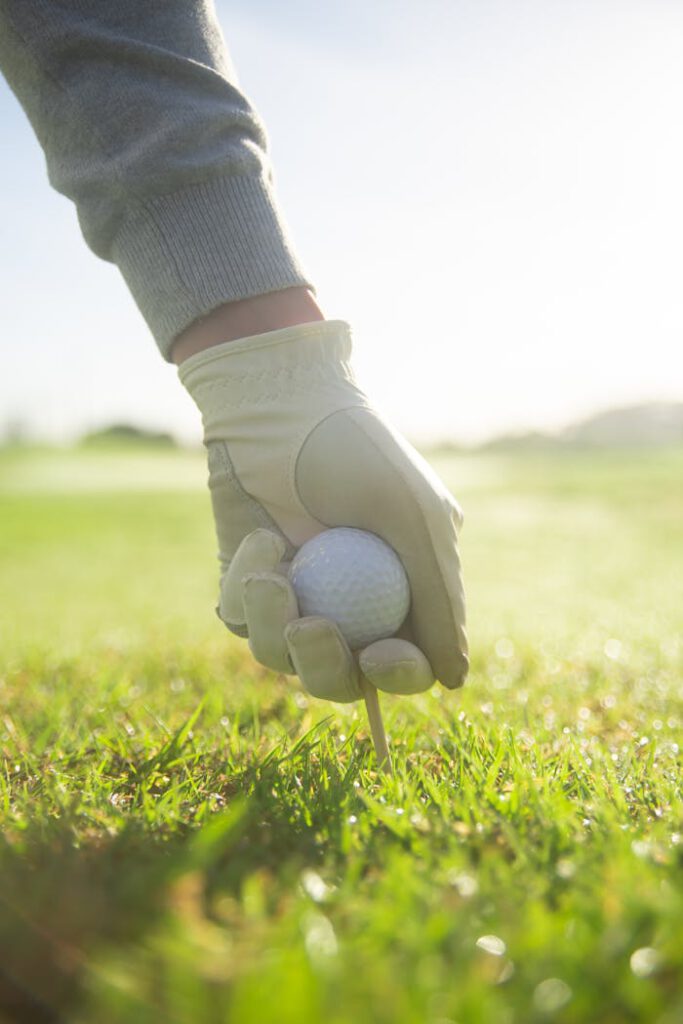 A Person Putting a Golf Ball with Tee on Green Grass